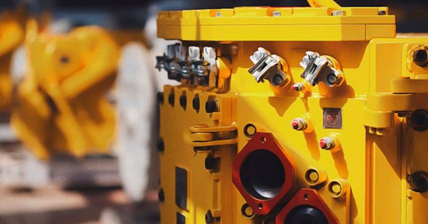 Row of yellow industrial pump housings with bolted flanges on a factory floor