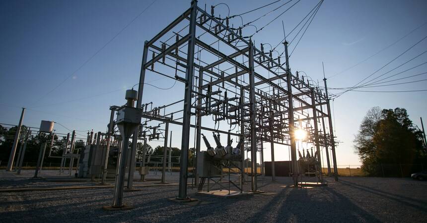 Electrical substation with steel lattice towers and power lines silhouetted at sunset