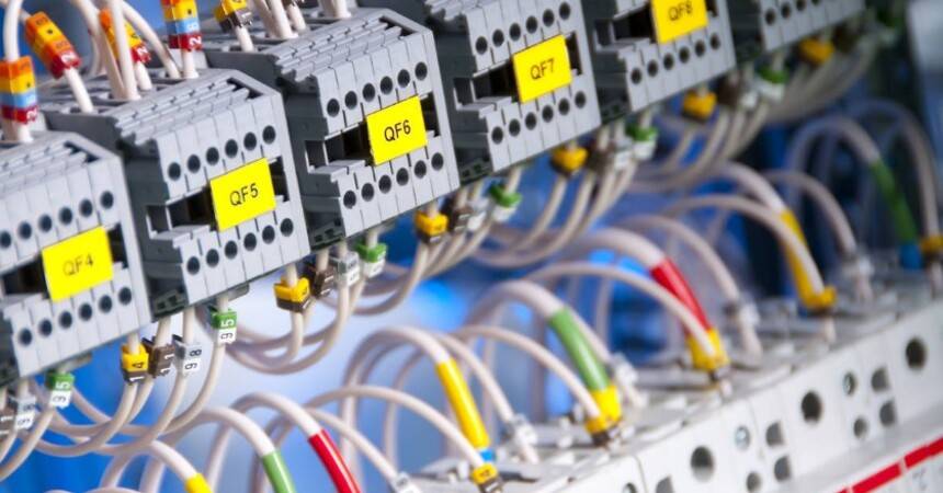 Row of yellow-labelled circuit breakers on a DIN rail with coloured control wiring