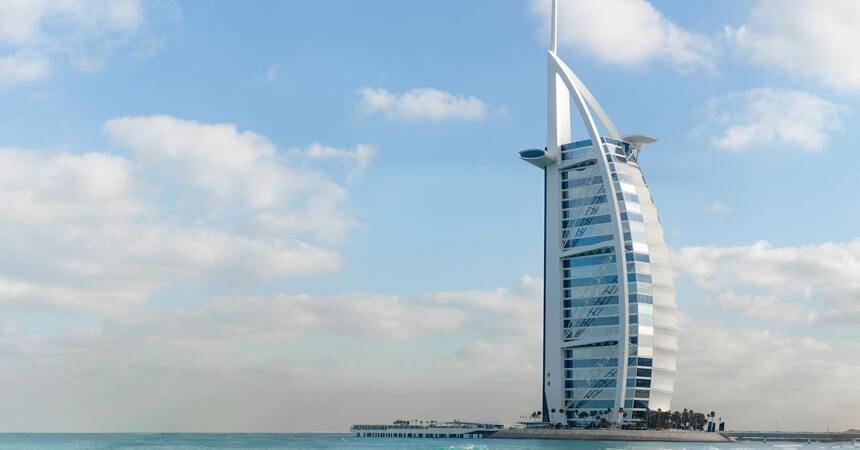 The sail-shaped Burj Al Arab hotel standing on the coastline under a bright sky