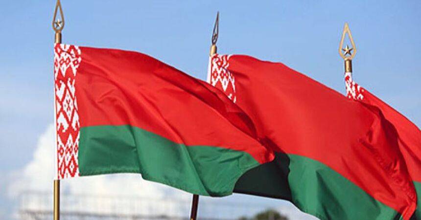 Three Belarusian national flags flying against a clear blue sky