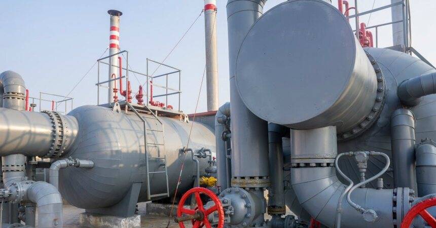 Large grey horizontal pressure vessels and pipework with red hand valves at an industrial plant